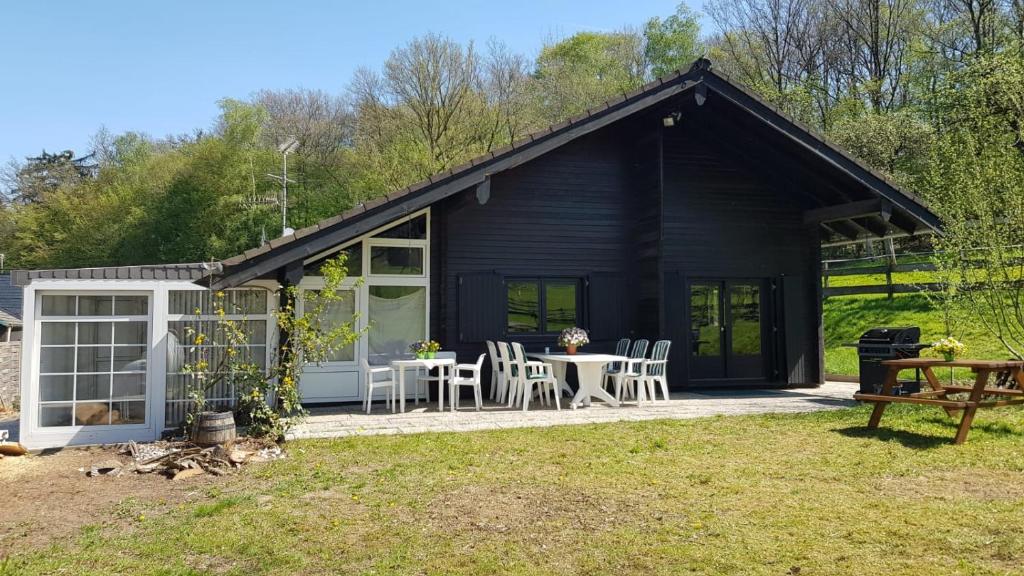 a black cottage with a table and chairs in the yard at Jagdhaus Malzhagen in Nümbrecht