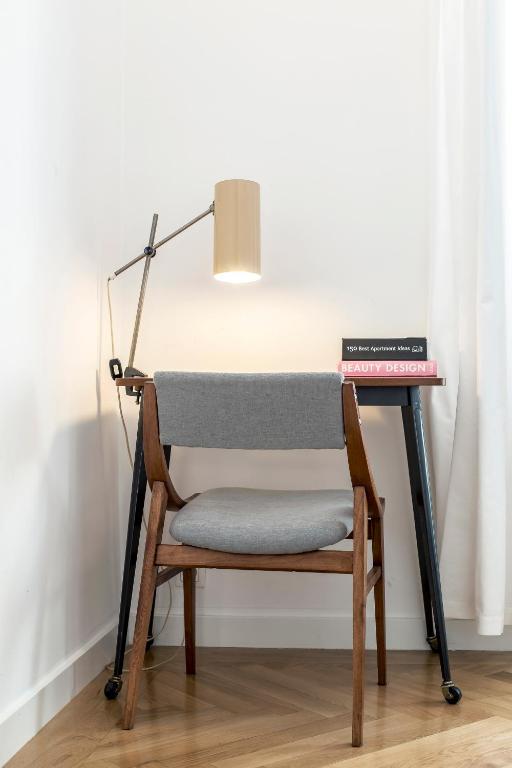 Small study nook with wooden chair, minimalist desk, task lamp, books beside curtained window.