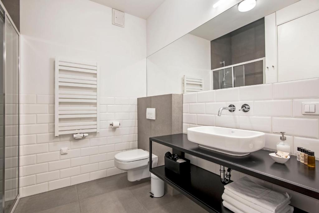 Modern bathroom with vessel sink on black counter, wall-mounted toilet, large mirror, towel radiator.
