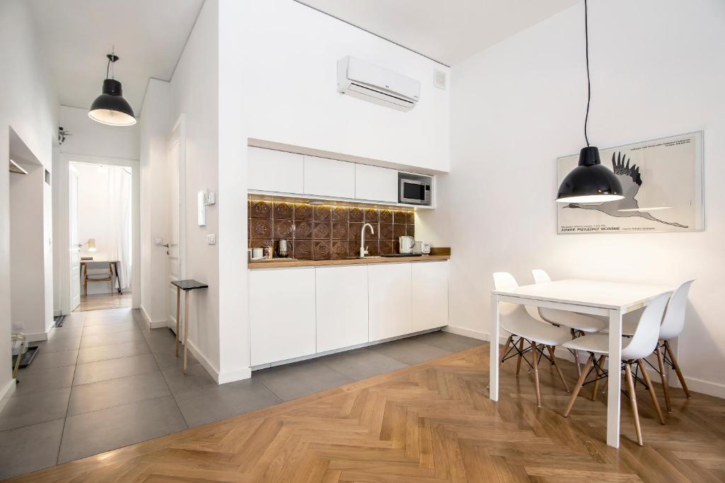 Compact kitchen and dining corner with white cabinets, decorative brown tile backsplash, pendant light.