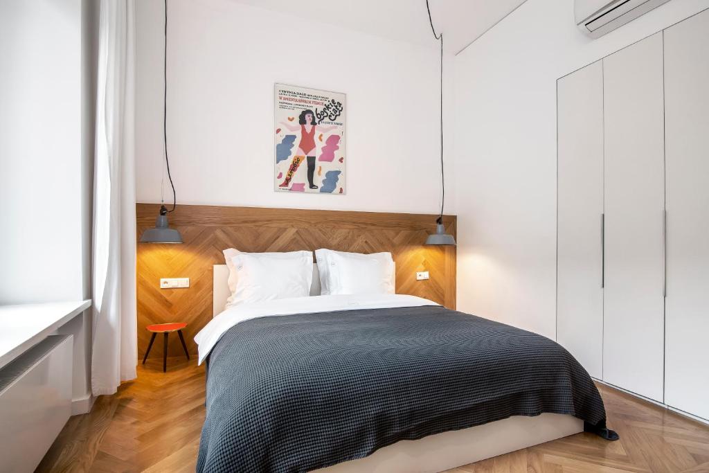 Double bed with chevron wood headboard, pendant lamps, gray bedspread, bright minimalist bedroom.