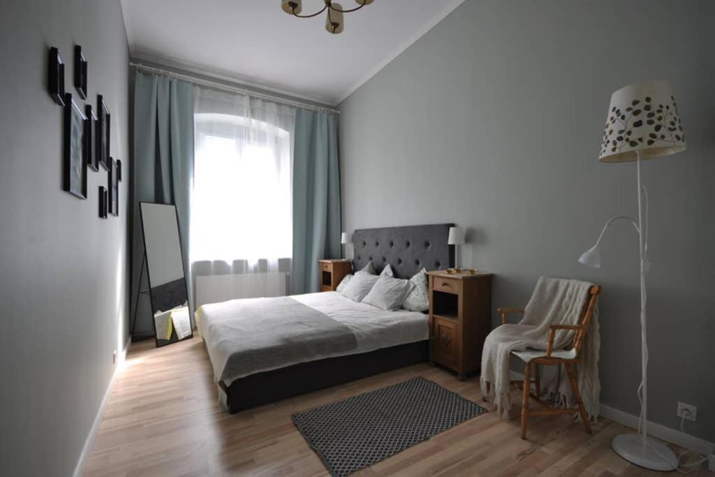 um quarto com uma cama, uma cadeira e um candeeiro em Poznańska Apartment em Poznań