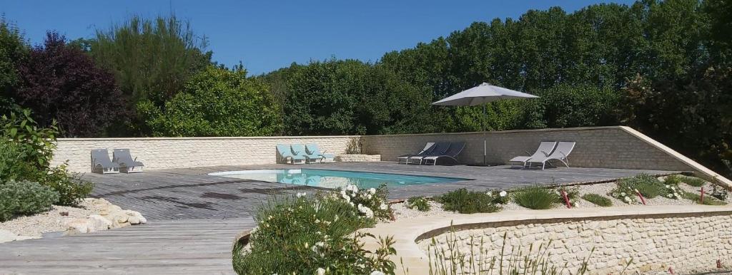 a swimming pool with two chairs and an umbrella at Les Prairies de l'Encrême in Céreste