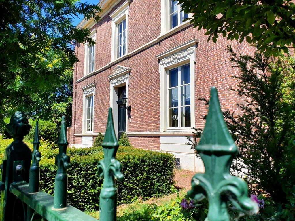 a green fence in front of a brick building at Boutique Hotel Villa de Proosdij in Klimmen