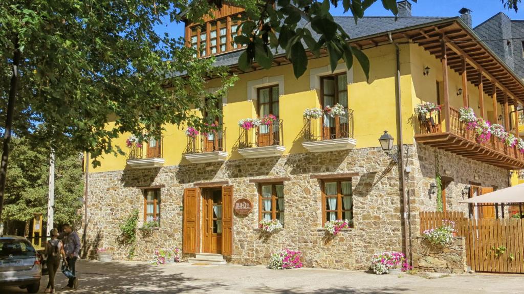 um edifício amarelo com caixas de flores nas janelas em Hotel Valle del Silencio em San Esteban de Valdueza