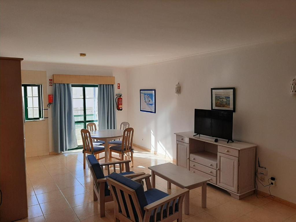 a living room with a table and chairs and a television at Dunas 107 in Alvor