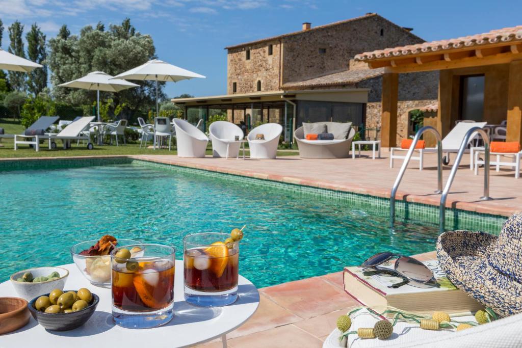 una mesa con bebidas junto a una piscina en Es Portal Restaurant i Hotel Boutique - Adults only, en Pals