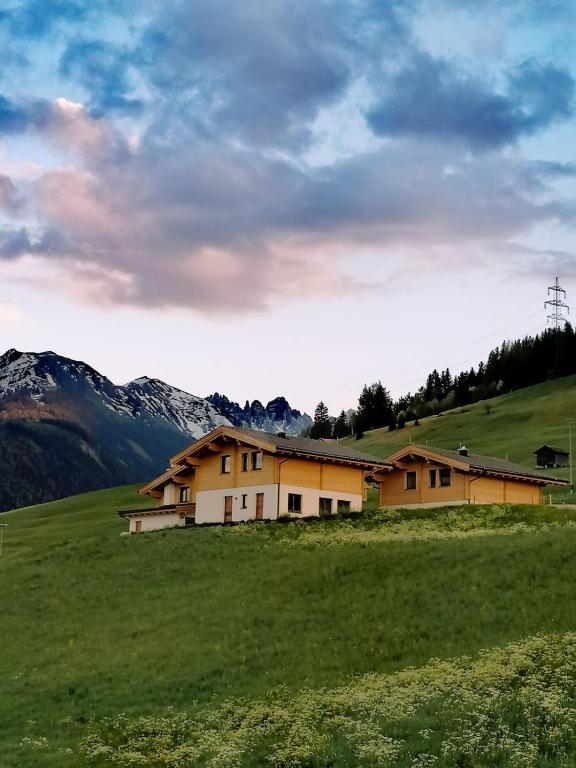 una casa in un campo con montagne sullo sfondo di Studler Hofchalets a Oberperfuss