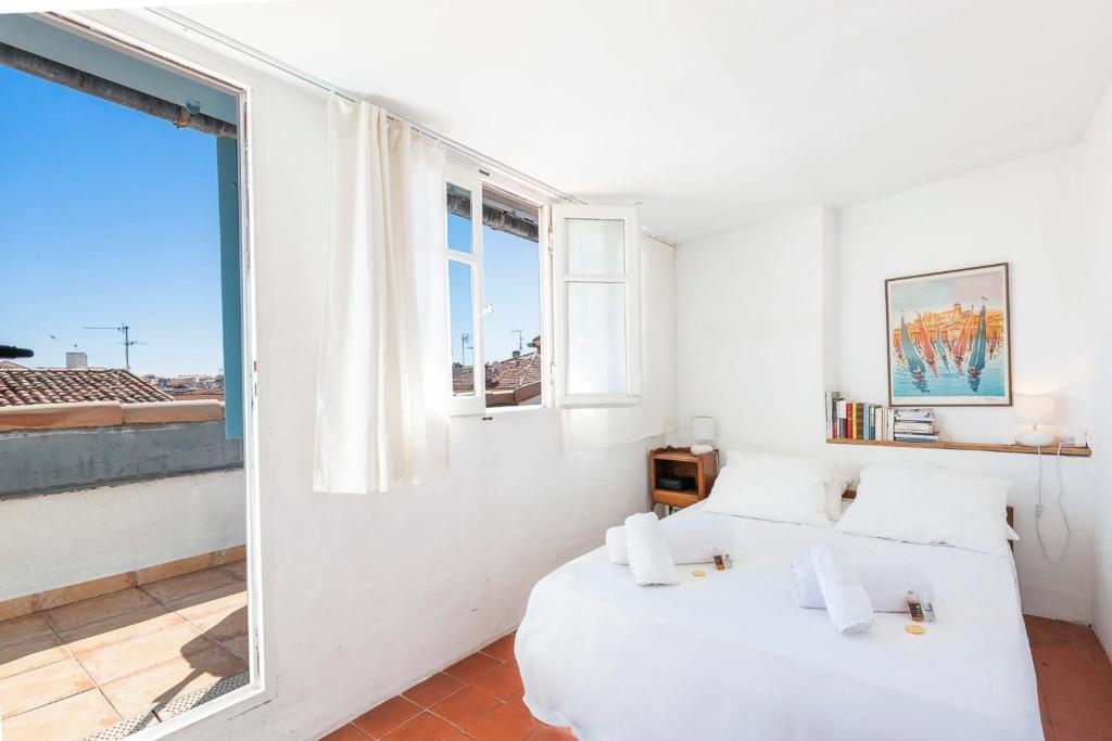une chambre blanche avec un lit et une fenêtre dans l'établissement Logement atypique dans la rue Fourmillière, à Antibes