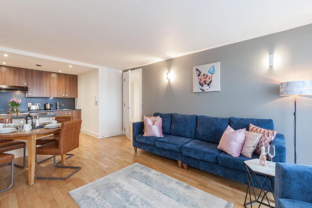 a living room with a blue couch and a kitchen at KSpace @ The Sinclair Building in Sheffield