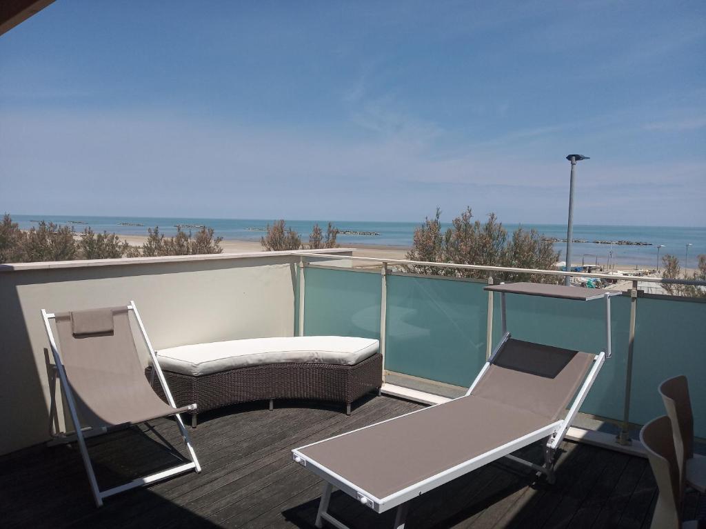 a balcony with two chairs and a couch and the beach at villa a mare in Senigallia