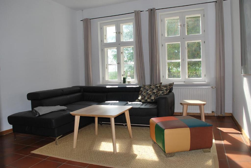 een woonkamer met een zwarte bank en een tafel bij Jasmundhus in Neddesitz