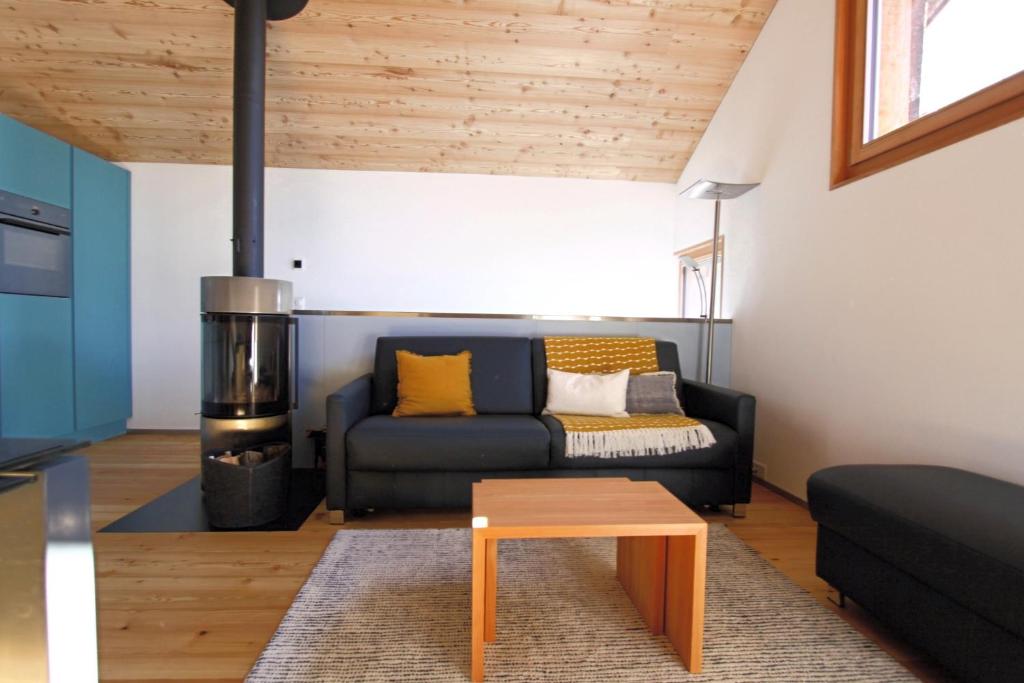 a living room with a black couch and a stove at Ferienhaus Z‘ Gädi in Ernen