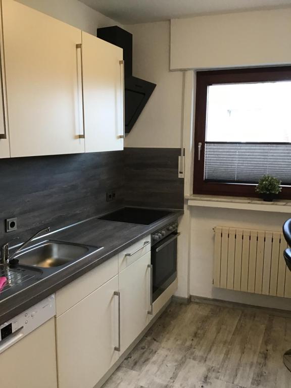 a kitchen with white cabinets and a sink and a window at Haus Dünenblick in Borkum