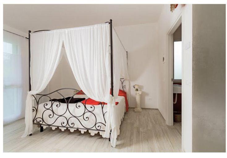 a bed with a canopy in a white bedroom at B&B Rabbit in Cervia