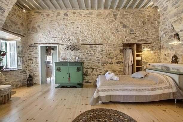 um quarto grande com uma cama e uma parede de pedra em Azura, traditional residence in Ano Syros em Ano Syros