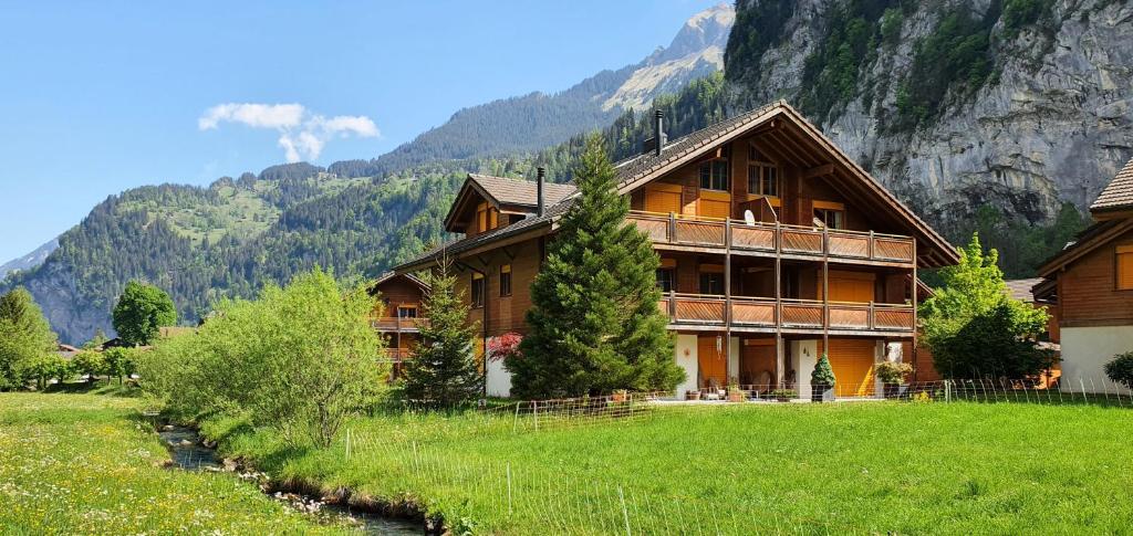 un grand bâtiment en bois avec une montagne en arrière-plan dans l'établissement Apartment Arven, à Lauterbrunnen