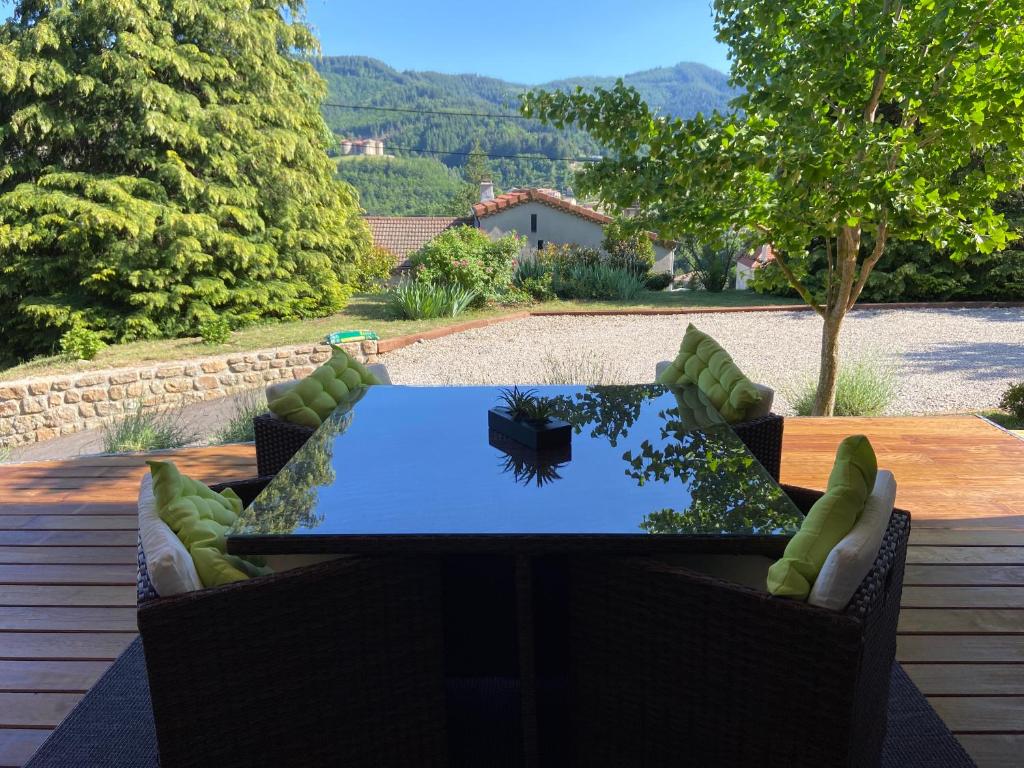 een patio met een tafel en stoelen in een tuin bij Chambre d'hôtes de la Riaille 400 m de la dolce via in Le Cheylard