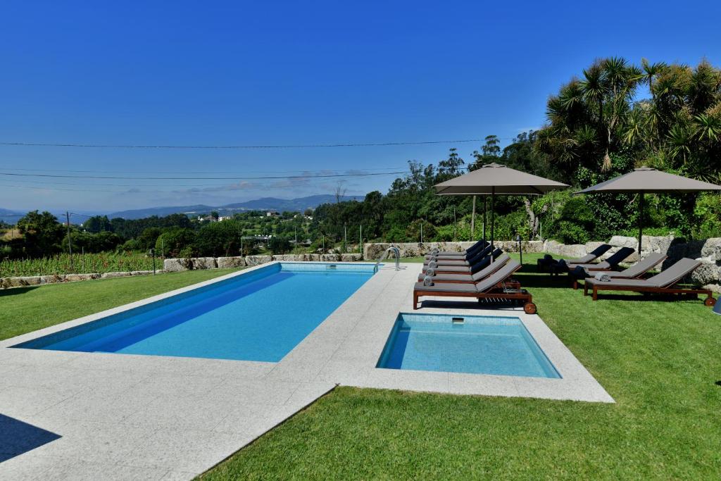 a swimming pool with lawn chairs and umbrellas at Vila Coura in Amarante