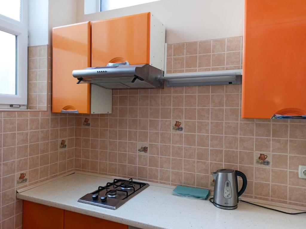 cocina con armarios de color naranja y horno con fogones en PANORAMI Apart Hostel in Lviv en Leópolis