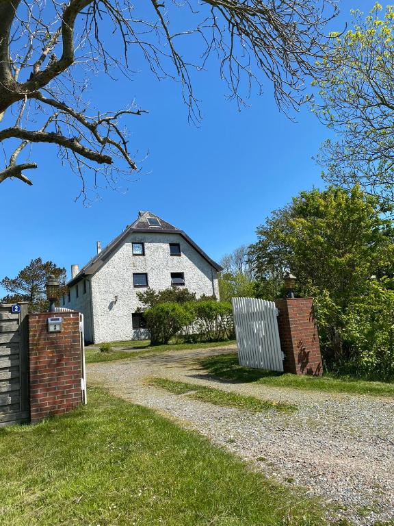 a white house with a brick fence and a driveway at Ferienwohnung Abendsünn in Nordstrand