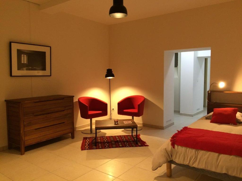 1 dormitorio con 2 sillas rojas, 1 cama y vestidor en Le Studio du Château, en Auriac-sur-Vendinelle