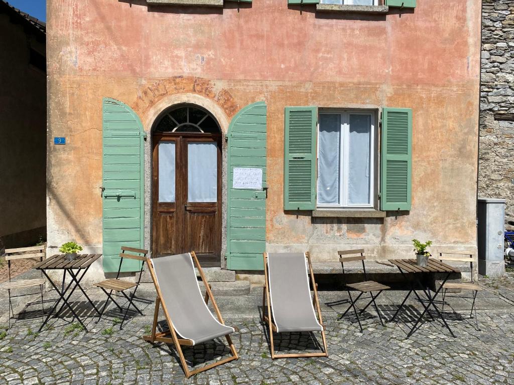un gruppo di sedie e un tavolo di fronte a un edificio di Casa Vino e Birra Boutique Guesthouse a Osogna
