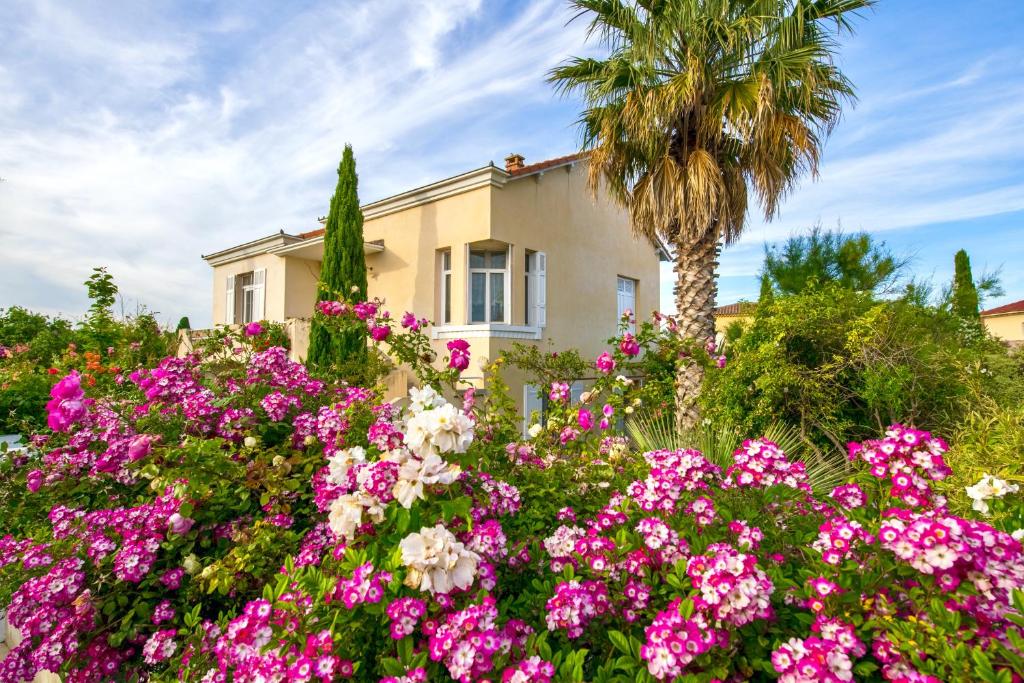ein Haus mit rosa Blumen und einer Palme in der Unterkunft La Villa ioanes in Port-Saint-Louis-du-Rhône