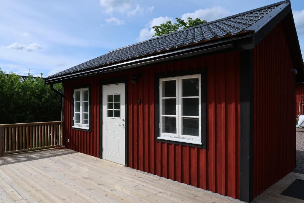 un hangar rouge avec des fenêtres blanches et une terrasse en bois dans l'établissement Ångsågen, à Skärblacka