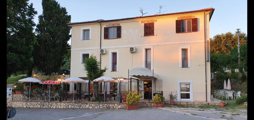 un gran edificio blanco con sombrillas delante en Locanda Fosca Umbra, en Narni