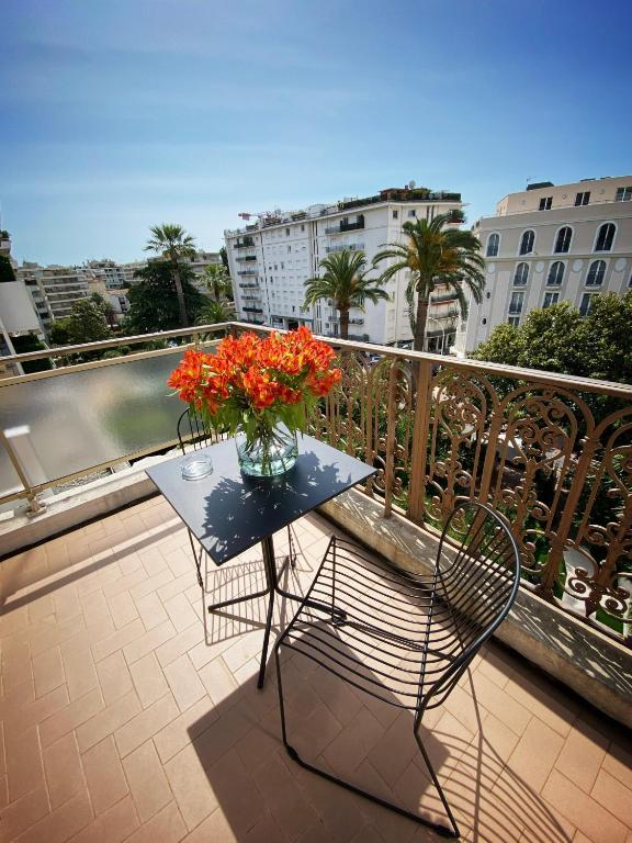 a table with a vase of flowers on a balcony at Hotel Molière in Cannes