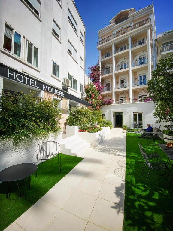 a hotel courtyard with tables and chairs in front of a building at Hotel Molière in Cannes
