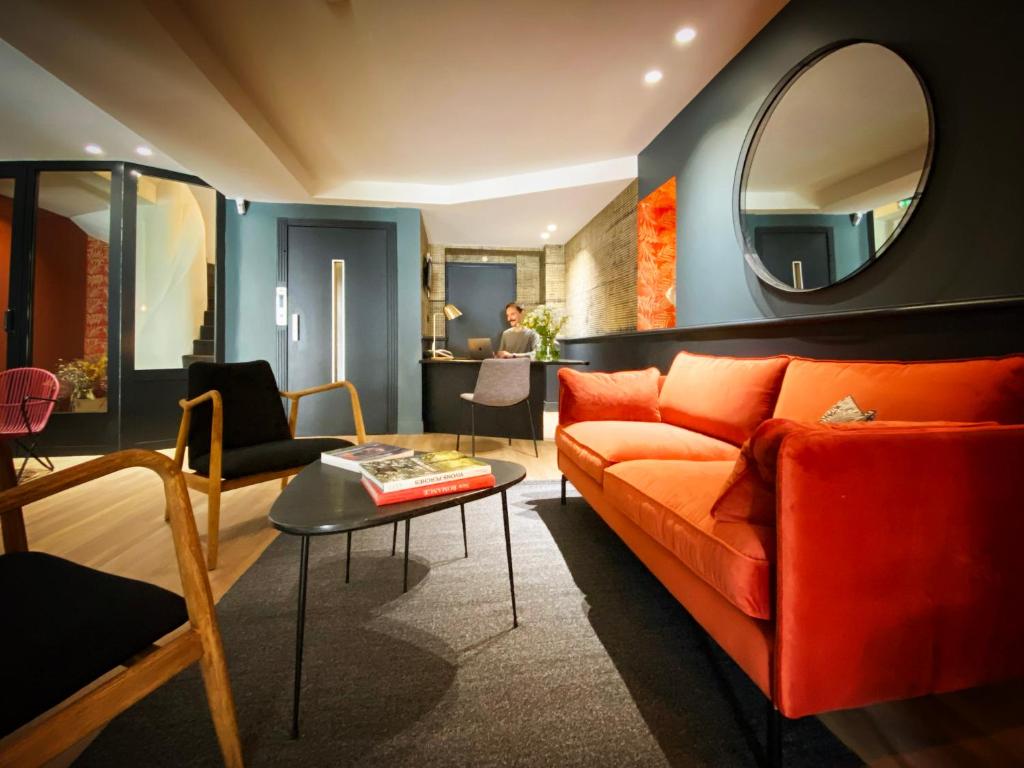 a living room with an orange couch and a mirror at Hotel Molière in Cannes
