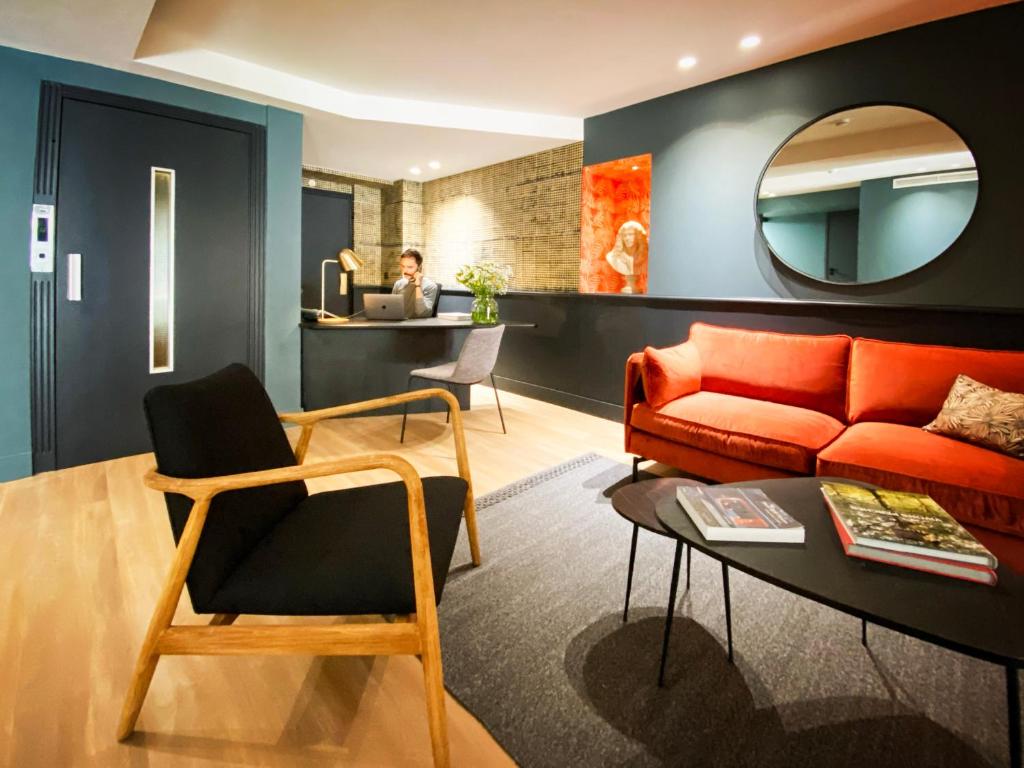 a living room with a red couch and a mirror at Hotel Molière in Cannes