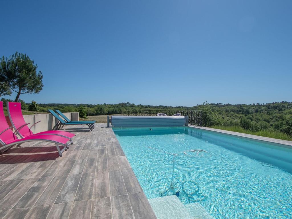 a swimming pool with two chairs on a wooden deck at Spacious Holiday Home in Sauveterre de l mance in Sauveterre-la-Lémance