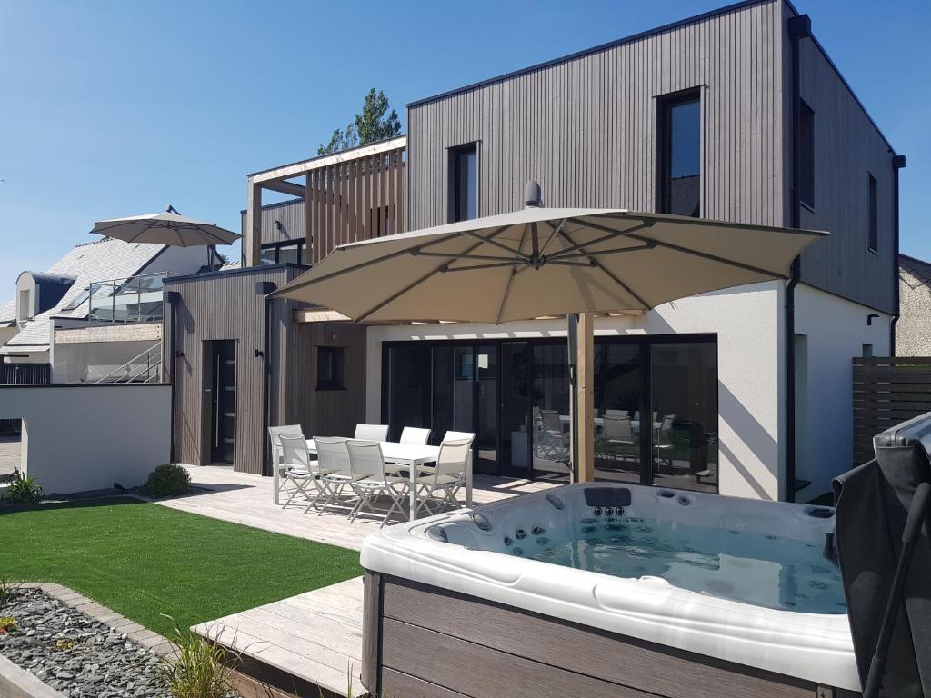 a backyard with a hot tub and an umbrella at Maison sur la Presqu'Ile de Rhuys in Saint-Gildas-de-Rhuys