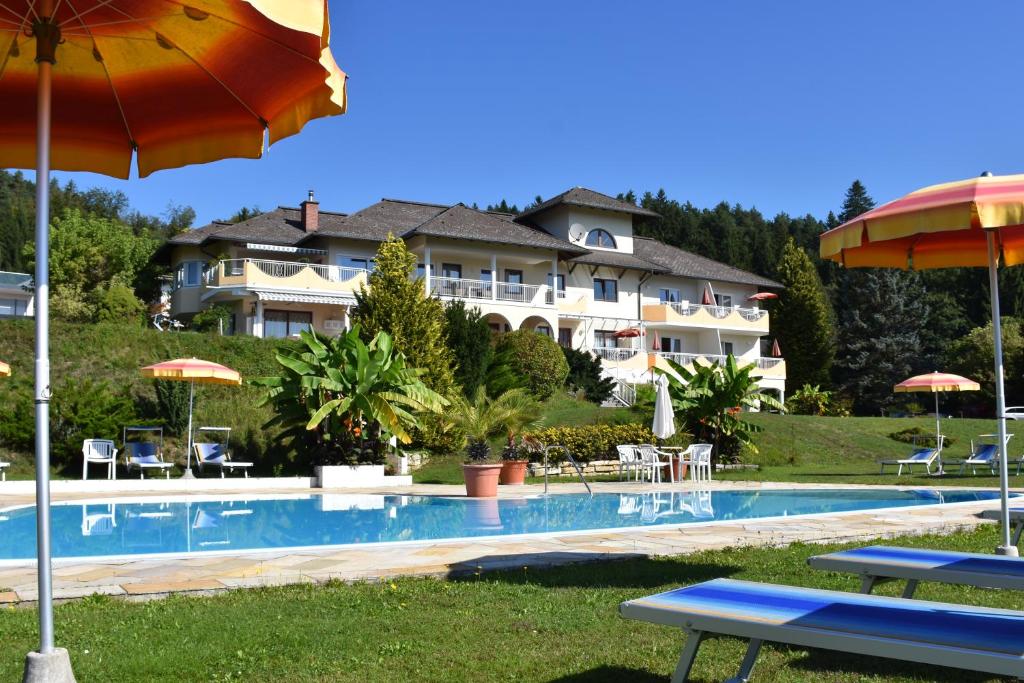 a large hotel with a swimming pool and an umbrella at Aparthotel Claudia in Velden am Wörthersee