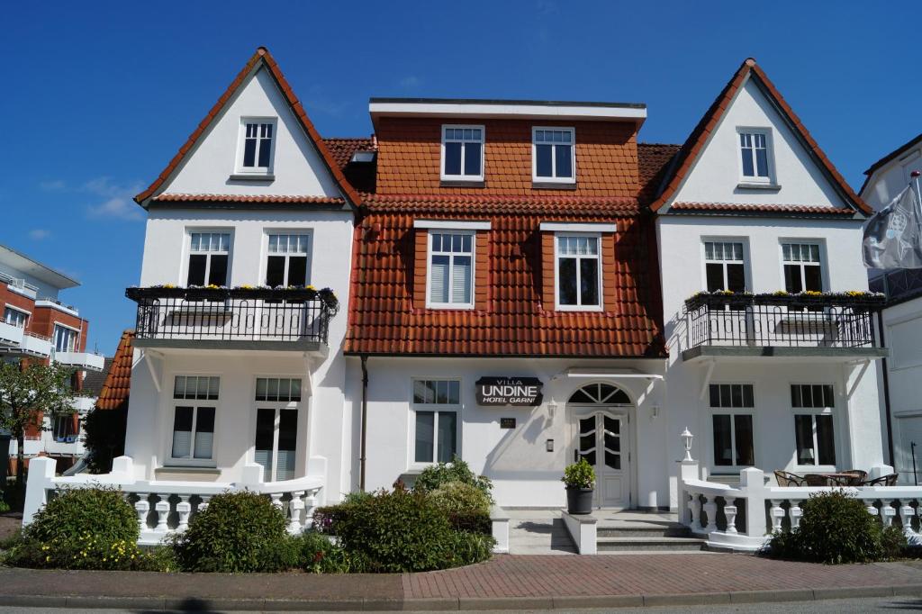 uma grande casa branca com um telhado vermelho em Hotel Villa Undine em Grömitz