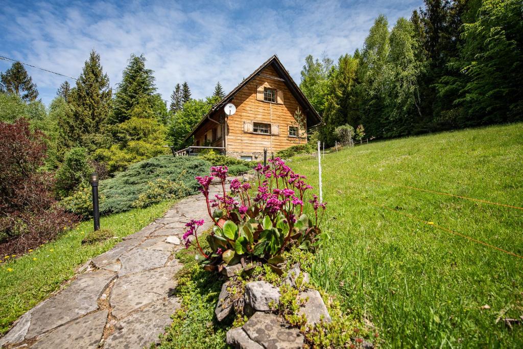 drewniany dom pośrodku pola z kwiatami w obiekcie Chata Jarzębata w Wiśle