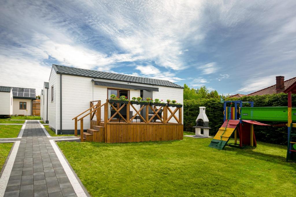 un patio trasero con una casa y un parque infantil en Domki z klimatem, en Ustka