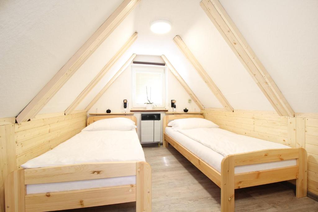 two beds in a attic room with a window at Pension Adel in Český Krumlov