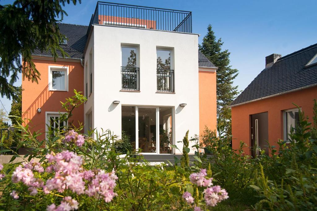 una casa con fachada blanca y flores rosas en Hospoda-Ferienhaus am Olba-See en Malschwitz