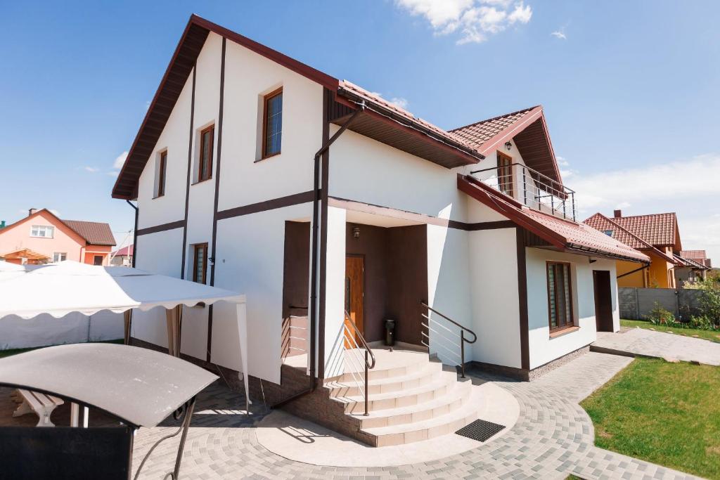 a white house with a patio and a white umbrella at Cottage Exclusive & dom4 in Grodno