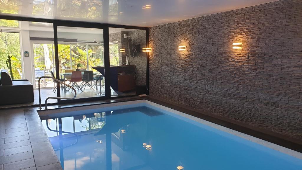 een zwembad in een kamer met een bakstenen muur bij Villa les Agapanthes avec piscine et SPA chauffée dans votre appartement in Hardelot-Plage