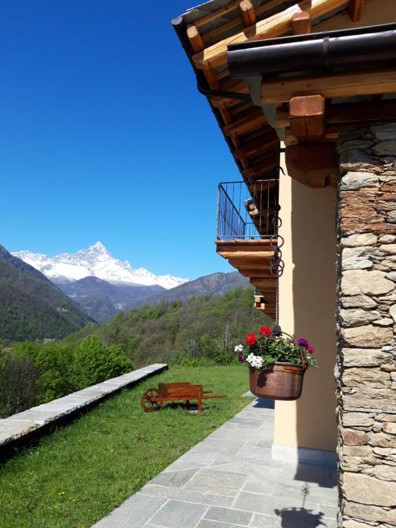 a building with a balcony with a bench and flowers at LA DRIT in Paesana