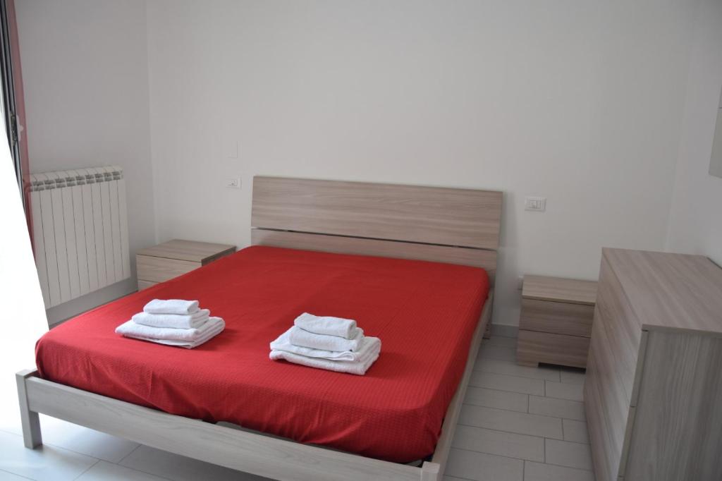 una camera da letto con un letto rosso e asciugamani di Casa di marco2 a Canosa di Puglia