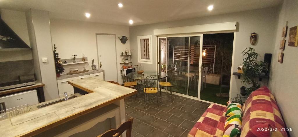 a kitchen and living room with a couch and a table at Secret Garden - Chez Gilles et Tra - Maison d hôte -T2 super mignon, neuf et indépendant , dans cadre agréable et zen in Valergues