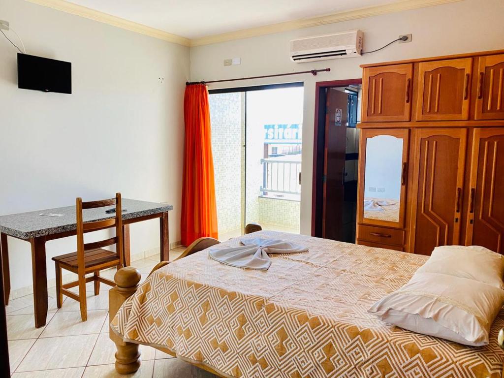 Un dormitorio con una cama, una mesa y un escritorio. en Hotel Universitário Goiatuba, en Goiatuba