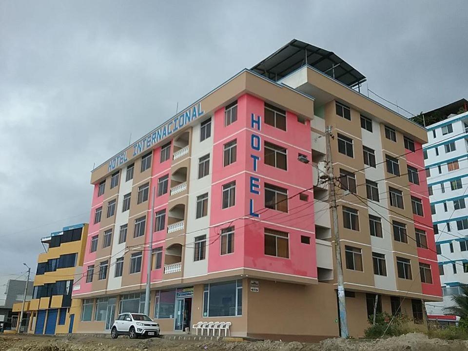 ein rosafarbenes Gebäude mit einem davor geparkt in der Unterkunft Hotel Internacional en Atacames in Atacames