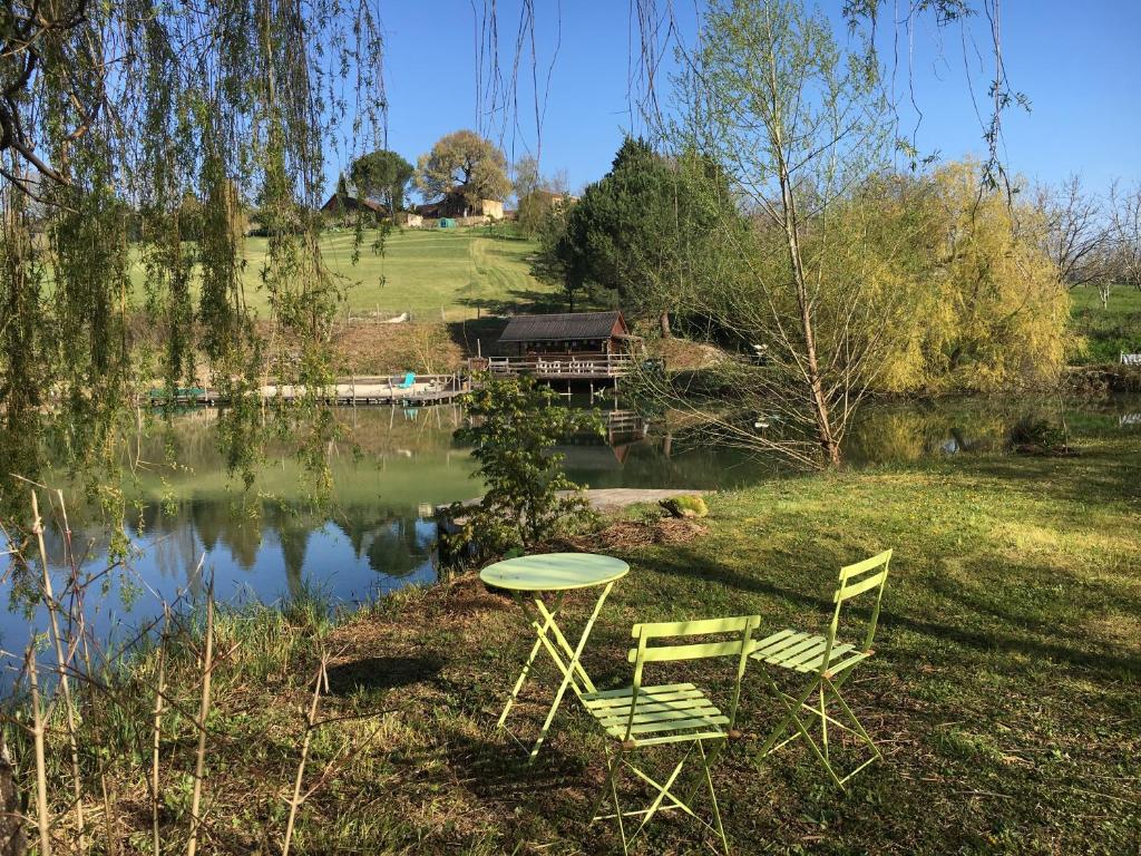 two chairs and a table next to a lake at Les Temps des Sources in Veyrines-de-Domme